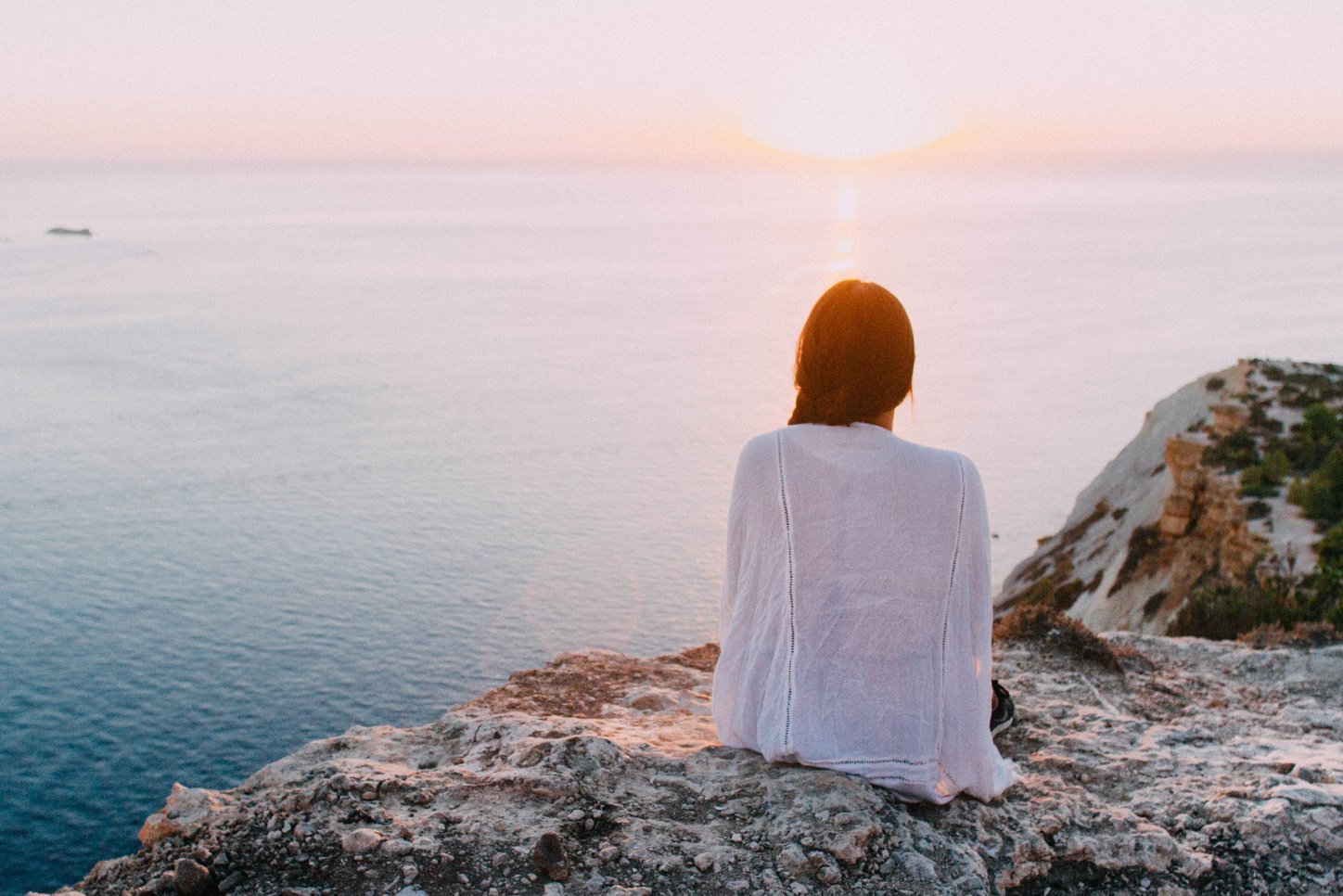 Woman Sitting on a Cliff at Sunset